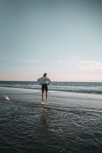 A vertical shot of a Caucasian female standing in the water on the beach in Florida