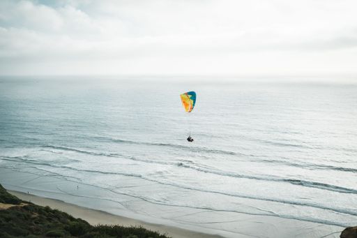 A paraglider over an island and coast during a gloomy sky