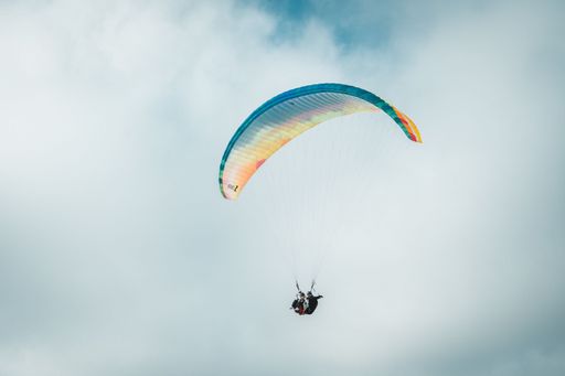 A paraglider flying against a cloudy sky
