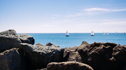 Beautiful shot of the sea with boats with rocks in the foreground