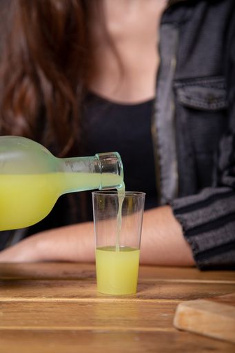 A vertical shot of a person pouring juice in a glass on the table