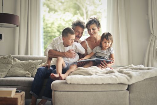 A cheerful happy family sitting on the sofa and looking at the pictures in a photo album