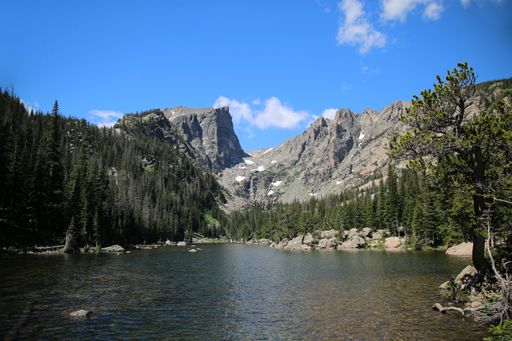A scenic view of a lake against green pine forest on slope of Rocky Mountains in Colorado, USA