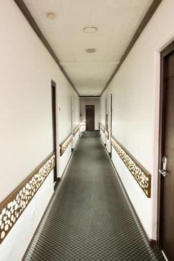 A vertical shot of the hallway of a building with white walls under the lights