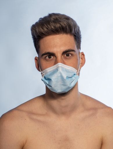 A shirtless Caucasian man wearing a medical mask for preventing the spread of COVID-19
