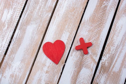 An overhead shot of a heart and a cross on a wooden surface - perfect for background