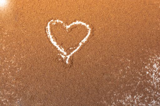 An overhead shot of a heart-shaped figure drawn on a surface of brown powder