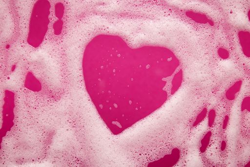 A heart shaped soap foam on a pink background