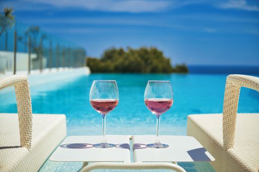 A closeup shot of two glasses of cocktail on a small table near the swimming pool