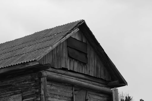 A grayscale shot of the top of  film old abandoned house in a rural areaa
