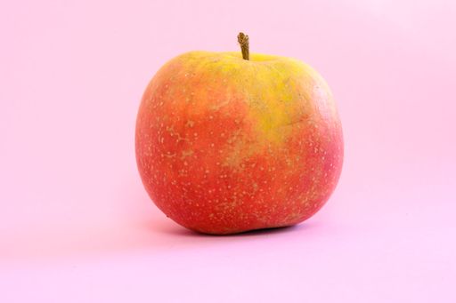 Fresh red ripe apple on a pastel pink background