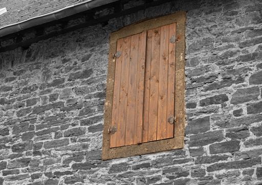 A closeup of a closed wooden window on a brick building