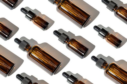 Group of Essential oil glass bottle with pipette. Variation of amber bottles. Pattern background