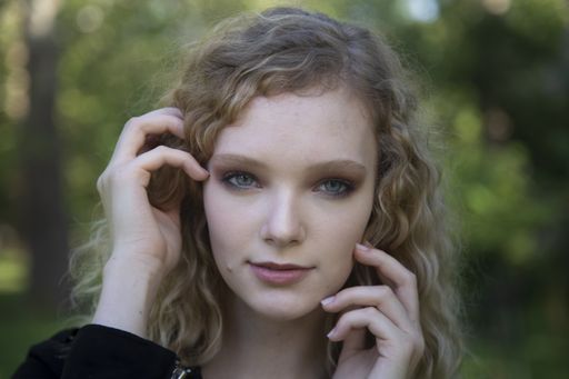 A closeup shot of a beautiful blonde female posing with her hands
