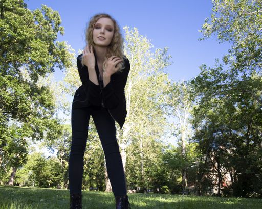 A beautiful female with blonde curly hair posing in a park