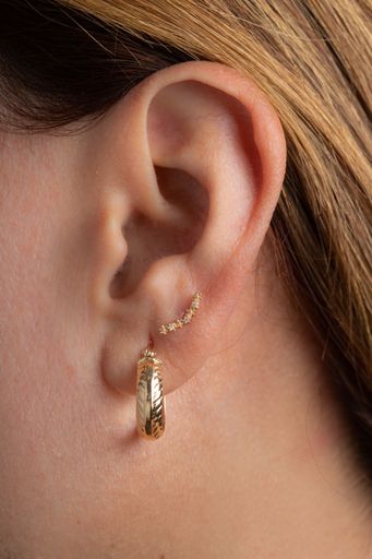 A closeup shot of the beautiful gold earrings on a female ear