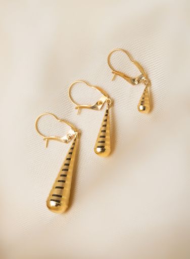 A closeup shot of a three pieces of golden earring with different sizes on a soft beige background