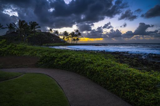 WARM SUNSET BREAKING THROUGH DARK CLOUDS NEAR THE PILI MAI RESORT ON KAUAI HAWAII IN THE EARLY EVENING