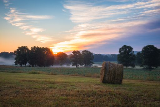 A green grassy field with a lot of hays at sunset in Sussex County, NJ