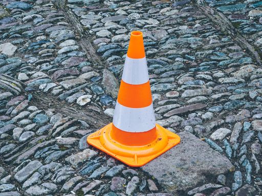 A closeup shot of an orange traffic cone on the road