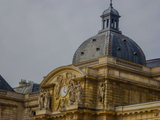 A low angle shot of the Luxembourg Palace under a cloudy sky in Paris, France