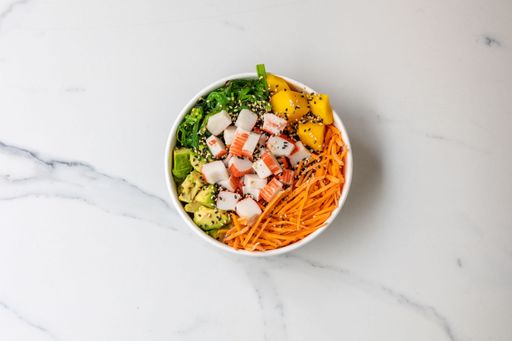 The top view of a bowl of healthy salad with veggies and crab