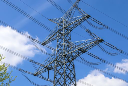 A low angle shot of a transmission tower under the cloudy sky