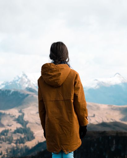 A vertical shot of a young girl looking down on the mountains