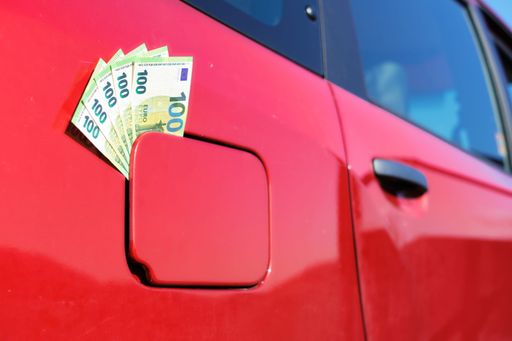 A bundle of one hundred euro banknotes in the fuel tank cap of a car. Symbol for the rising fuel price.