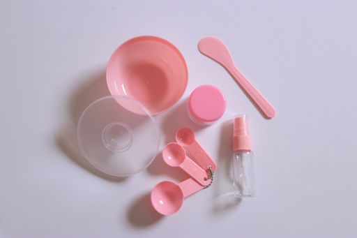 A top shot of pink skincare facial mask tools with white background