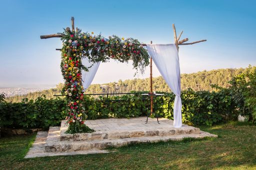 A beautiful wedding arch decorated with colorful flowers and white curtains in a garden