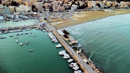 The view of the boats in the harbor with city buildings in the background.