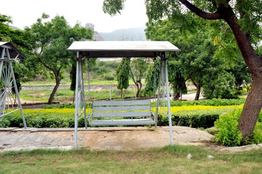 A white outdoor swing cahir in a garden