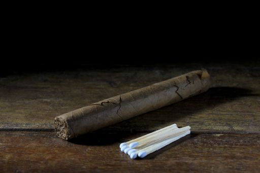 A closeup shot of a cigar and matches on a wooden table