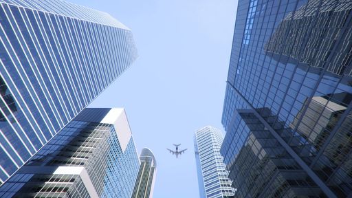 A low angle shot of an airplane flying above modern skyscrapers in city center