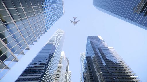 A Low angle shot of an airplane flying above modern skyscrapers in city center