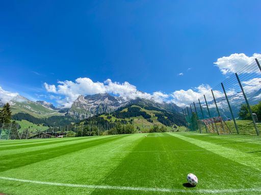 The soccer field with mountains in the background in Adelboden village Switzerland against a blue sky