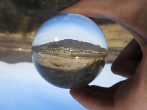 A closeup shot of a male holding a crystal ball with a landscape reflected