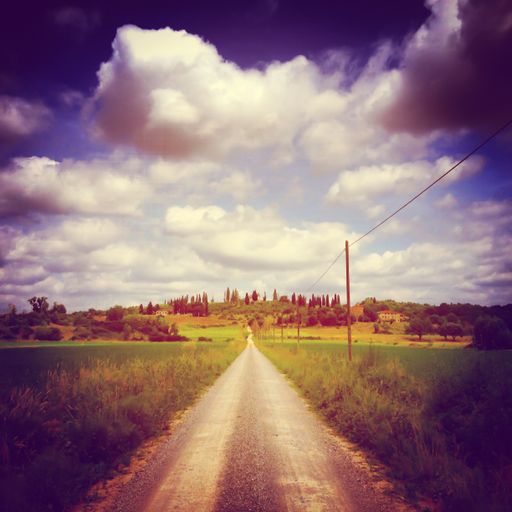 A beautiful shot of a pathway in the middle of a green field under the breathtaking cloudy sky