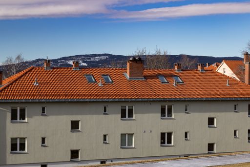 A view of an apartment building with a red roof on a sunny day