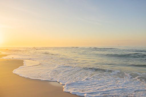 A scenic view of a sandy beach against the seascape at sunset in Fort Morgan, Alabama