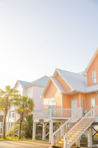A vertical shot of beautiful colorful houses and palm trees on the street on a sunny day in Fort Morgan, Alabama