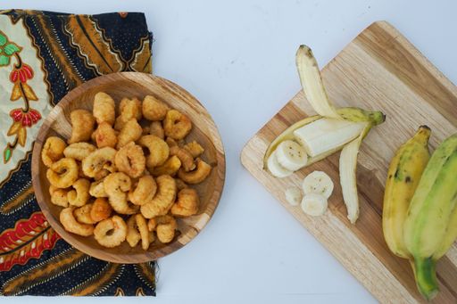 A top view of fried shrimps and small bananas on a cutting board