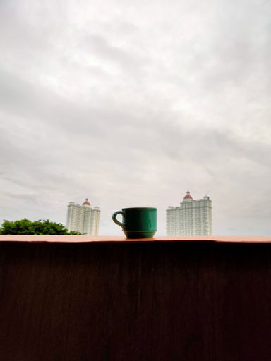 A vertical shot of a cup of coffee with a scenic view