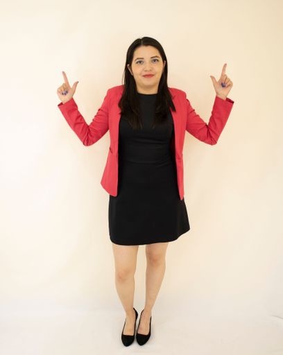 A modern business woman, gesturing with her hands, standing near a white wall
