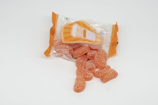 A closeup of sweet orange candies in a plastic pack isolated on a white background