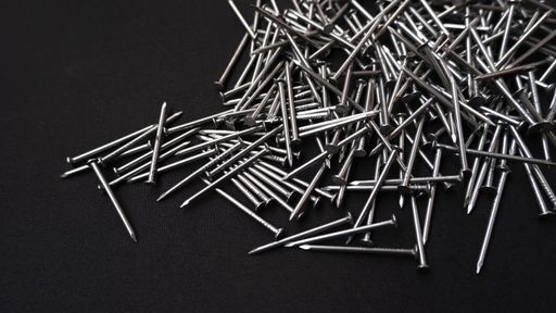 A panoramic shot of a pile of steel nails on a black background