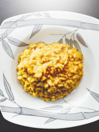 A vertical shot of delicious risotto in a white plate on a grey surface