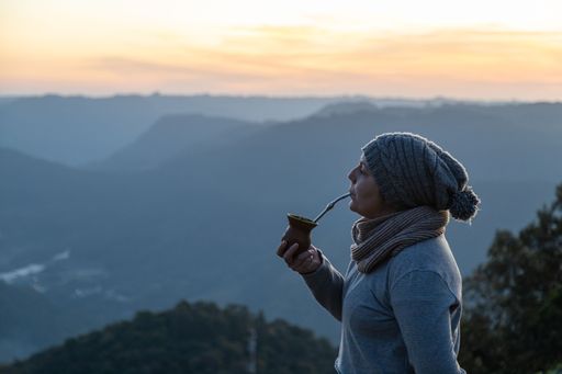 Woman drinking yerba mate drink on the morning on the top of a mountain, Rio Grande do Sul highlands, Brazil