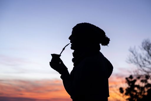 Silhouette of a woman with a cap drinking yerba mate, traditional South American drink, at sunset. Twilight sky